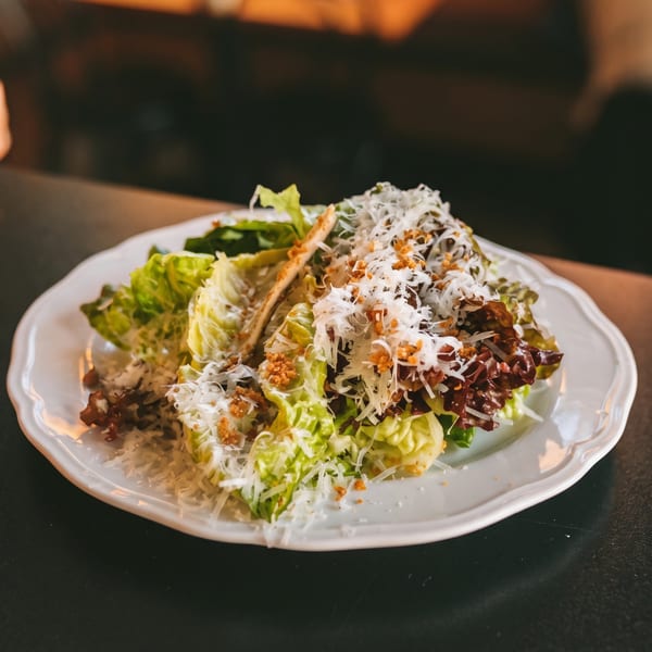 A fresh Caesar salad with romaine lettuce, croutons, and parmesan cheese on a white plate.